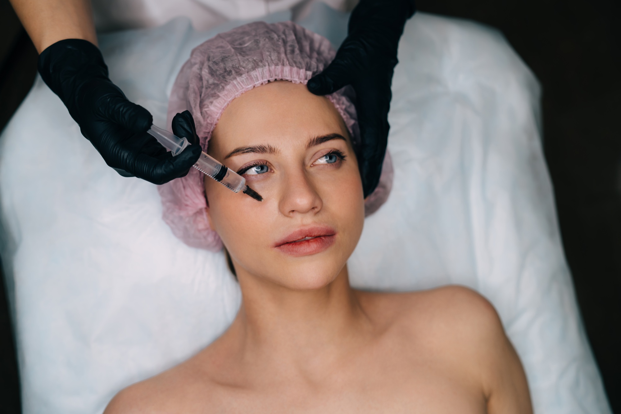 Beautician do botox injection with syringe to girl